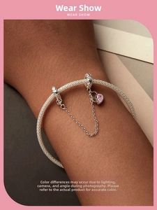 Detail of silver safety chain with pink heart charm on braided bracelet with pavé clips