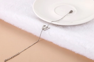 Detail of silver titanium bracelet with a rhinestone-encrusted letter W charm on a plate