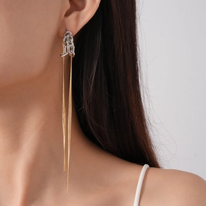 Detail view of long metal tassel earrings with gold and silver chain link contrast