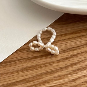 Close-up of handmade freshwater pearl bow ring on a natural wooden background