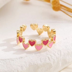 Dettaglio anello dorato regolabile con cuori in smalto rosa su base in pietra
