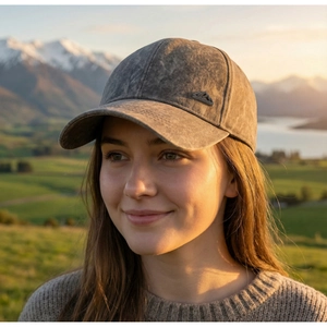 Close-up of vintage grey baseball cap with mountain logo in a scenic outdoor setting
