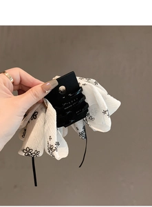 Détail d'une pince à cheveux avec nœud en tissu floral aux motifs noirs et blancs