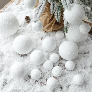 White foam snowball Christmas tree ornaments in various sizes on a snowy winter background