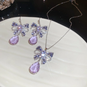 Macro detail of butterfly teardrop necklace and earrings with sparkling purple zircon