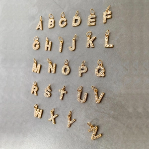 Flat lay of 26 gold stainless steel alphabet charms with clear cubic zirconia stones