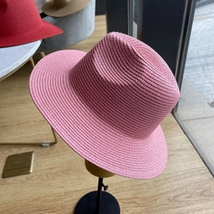 Detail of pink woven straw sun hat showing the intricate texture and fedora style