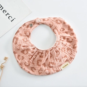Detail of soft cotton baby bib featuring pink leopard print and ruffled edges with snap