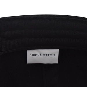 Detail of 100% cotton material label on the inside of the black baseball cap