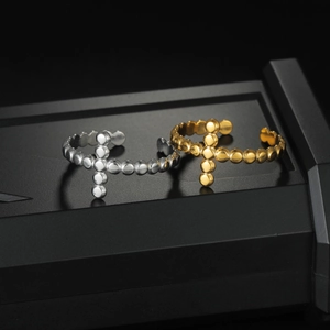 Cross shaped gold and silver stainless steel open rings on black showcase