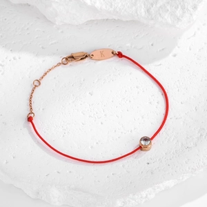 Détail du bracelet en corde rouge avec fermoir or rose et pendentif lettre K serti