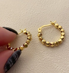Detail showing S925 hallmark on gold geometric beaded hoop earrings held by hand