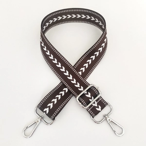 Detail of adjustable nylon guitar strap in dark brown with white arrow pattern and silver hooks