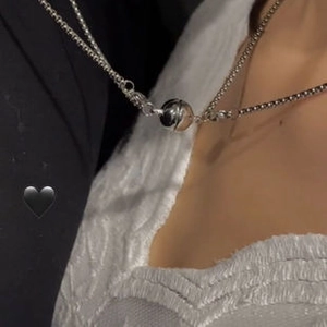 Close-up of magnetic ball pendants attracting each other on silver couple necklaces