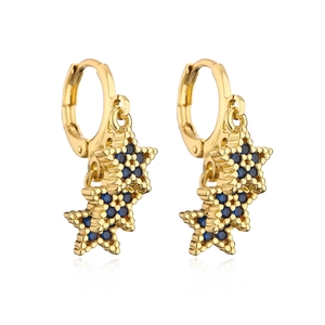 Detailed view of gold-plated star earrings with blue zircon inlays on a white background
