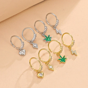 Detail view of heart, square, leaf, and lightning charms on gold and silver hoop earrings