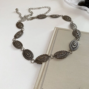 Close-up of silver oval metal waist chain with vintage texture on white background