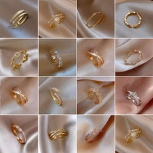 Detailed overview of 16 floral and crystal gold and silver fashion rings on silk fabric