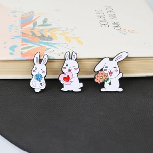 Detailed view of three cute enamel white rabbit pins with lollipop heart and flowers