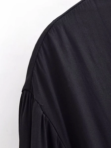 Macro detail of the shoulder stitching and sleeve seam on this casual black blouse