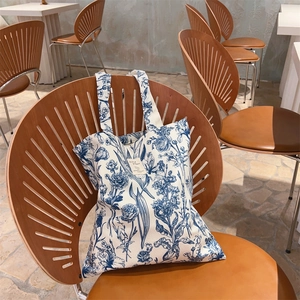Detail of French vintage canvas tote with blue floral pattern on a cafe chair