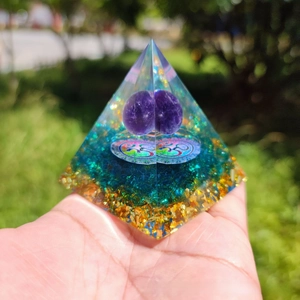 Macro shot of an Orgone pyramid with an amethyst sphere, Om symbol, and gold foil base