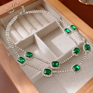 Close-up of emerald-cut green stone necklace with micro-paved rhinestones in a wooden box