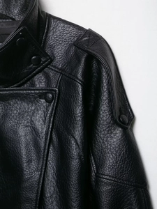 Close-up of black faux leather jacket with lychee texture, epaulettes and metal snaps