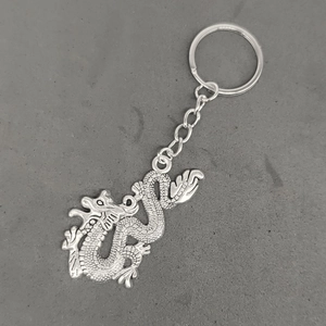 Detail view of a vintage silver dragon pendant keychain with a rustic metallic finish