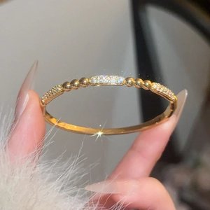 Detail view of gold-plated bangle with pavé zircons and decorative beads in soft light