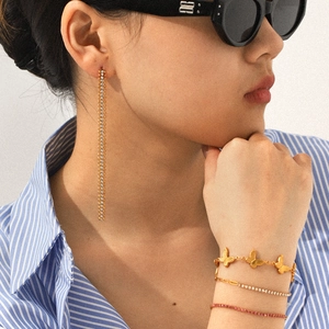Model wearing silver tassel drop earrings and layered butterfly bracelets with zircons