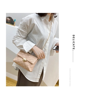 Close-up of beige quilted crossbody bag featuring a golden lock and elegant chain strap