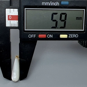 Primer plano de un colgante de nácar en forma de gota midiendo 5,9 mm con un calibre digital