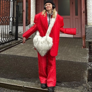 Close-up of a white heart-shaped faux fur shoulder bag paired with a red winter outfit