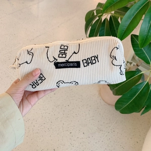 Détail de la texture en velours côtelé doux et étiquette merciparis sur la trousse beige