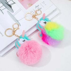 Detail view of pink and rainbow unicorn fur ball keychains with metallic ring attachments