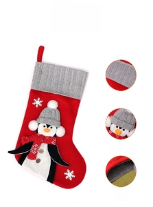Close-up of red velvet Christmas stocking with gray knit cuff and penguin applique