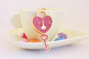 Close-up of golden heart lock keychain with rose red rhinestones and a small key