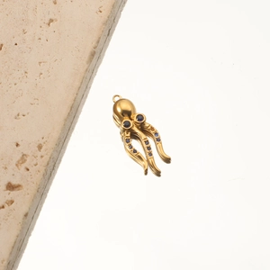 Detailed macro view of an 18K gold-plated octopus pendant with blue gemstone eyes
