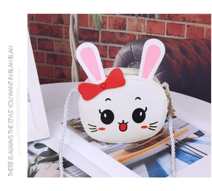 Detail of white rabbit mini shoulder bag with 3D ears, red bow and woven rope strap