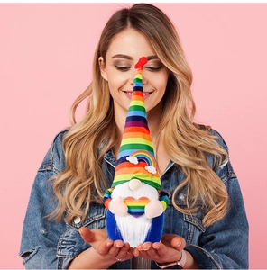 Detailed view of a plush rainbow gnome with a striped hat and a colorful heart ornament