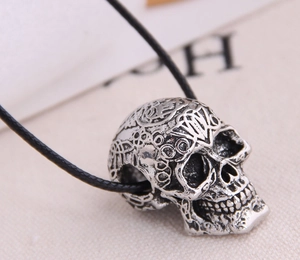 Detailed close-up of a silver skull pendant with intricate engravings and black cord