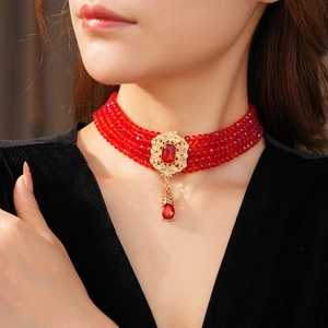 Macro view of a vintage multilayer red crystal choker with a gold floral pattern pendant