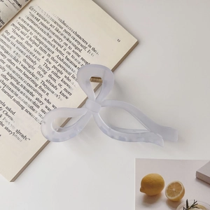 Detail of light blue translucent bow hair claw clip with golden metal spring