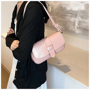 Detail of light pink faux crocodile pattern underarm bag with unique knotted strap detail