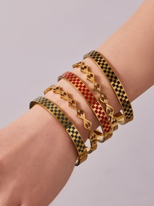 Detail of stacked stainless steel gold bangles with checkered enamel and crystal accents