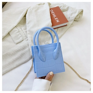 Close-up of blue crocodile pattern mini handbag with golden chain strap and top handle