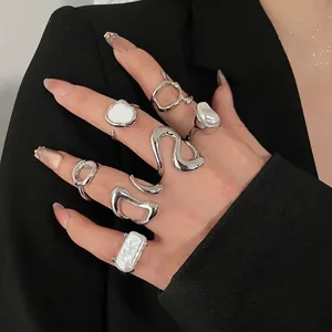 Minimalist silver rings set with irregular pearls and white enamel on a black suit background