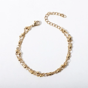 Detailed view of double-layered gold chain bracelet with beads and lobster clasp closure