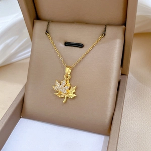 Macro shot of double-layered maple leaf pendant with white crystals and golden finish